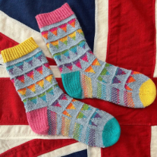 Socks knitted in a gradient and neutral featuring eight strings of triangular bunting.