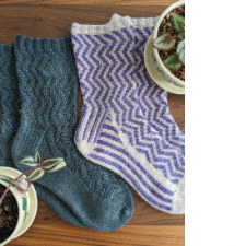 Socks with a vertical chevron pattern. One pair has the design as a texture, the other as colorwork.