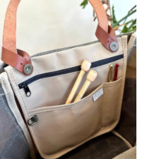 Flat canvas bag has lots of pockets. Loops connect it to the handles of a tote, or you can wear it on its own with a shoulder strap.