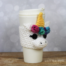 Adorable unicorn head with 3D nose, and colorful flowers crocheted at the base of its horn, wrapped around paper takeout cup.