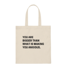 White tote with black lettering in all caps reads “You are bigger than what is making you anxious.”