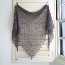 This triangular Shetland Lace shawl is knitted all in one piece and incorporates a garter stitch centre, borders of rose trellis and tree motifs and is finished with simple lace edgings.