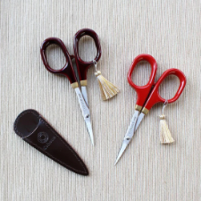 Two pairs of small scissors with richly lacquered wood handles that look like porcelain.