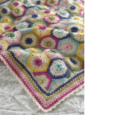 Granny hexagons with puffy flowers in the center of each, made into blanket with striped edge.
