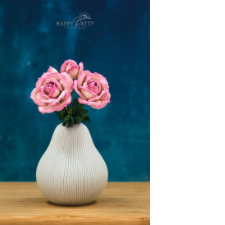 Three crocheted roses with leaves in a pear-shape vase.