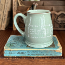 Cottage-style ceramic mug in celery with white writing reads, “All we have to decide is what to do with the craft that is given us.”
