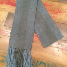Fringed scarf in dark neutrals. Scarf is striped lengthwise into three color blocks. The outer two are gray and the inner one is taupe.