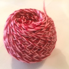 Cake of deep red and medium pink plied yarn.