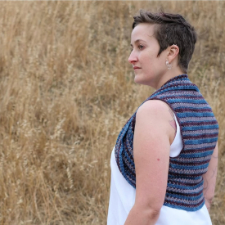Woman in field wears knitted sleeveless vest-style shrug.