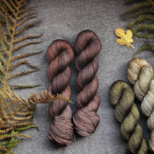 Chocolate brown skeins shown with an olive tonal skein and a variegated honey and cream skein.