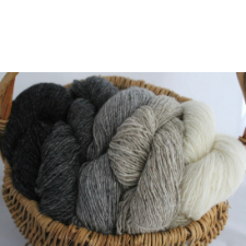 Five shades of yarn from cream to black in a rustic basket.