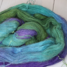 Laceweight silk and suri alpaca yarn in purple, aqua, and green.