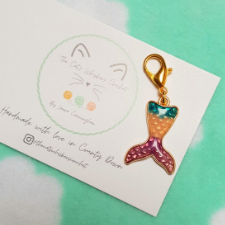 A enamel mermaid tail charm in green, gold and deep red, with a lobster clasp.