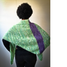 Woman shown from the back, wearing triangular shawl divided vertically into a trellis stitch section stockinette in a deep color near the center, then a textured section in the same color as the trellis stitch.