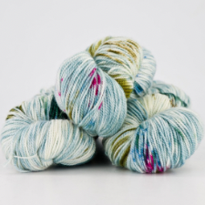 Stack of variegated yarn in light blue and white with pops of celadon, spruce green and hot pink.
