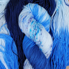 Variegated yarn in true blue and white that includes tonal portions and speckles.