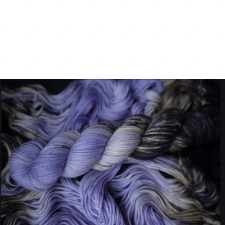 Dark lavender variegated yarn fades to black with splashes of cream and hints of navy.