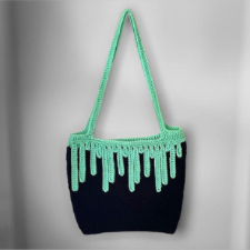 Black squarish tote with mint green shoulder straps, and a mint green border around the top that “drips” mint green trails of slime down to the halfway point of the bag.