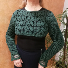 Woman wears long-sleeve crop top over longsleeve shirt. The torso of the bolero has vertical columns of leaves.