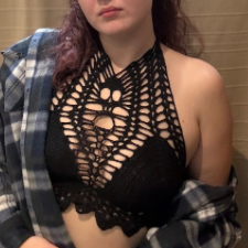 Woman wears black halter top with lacy bottom edge, solid bra cups, then lace from the cups to the neck closure. A crocheted skull features prominently.