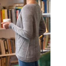 Long cardigan with cables where stays would be in a highly structured garment. Cardigan is open front and has three cables down the spine as well.