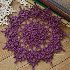 Eleven inch or 28 centimeter diameter doily that comes to points and has a very open section toward the middle radially. Made with number 10 crochet thread.