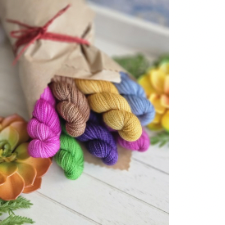 Pink, tan, gold, periwinkle, fuchsia, purple and green mini skeins wrapped in brown paper like a floral bouquet.