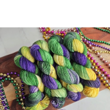 Four hanks in Mardi Gras purple, gold and green, strewn with Mardi Gras beads.