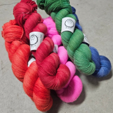 Hanks of semisolid yarn in coral, red, pink, green and blue.