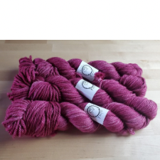 Three hanks of tonal red-violet yarn.